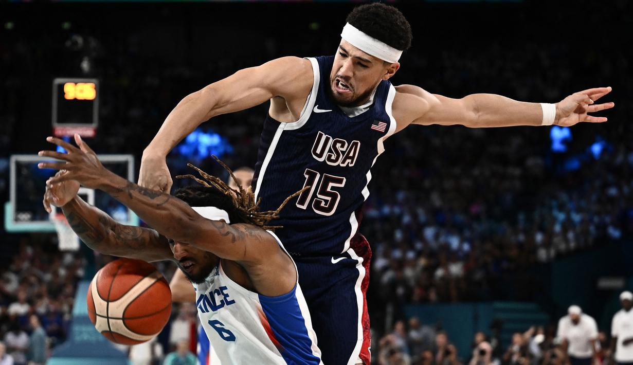 Pebasket Prancis, Andrew Albicy (kiri) berebut bola dengan pebasket Amerika Serikat, Devin Booker pada pertandingan final Olimpiade Paris 2024 yang berlangsung di Bercy Arena, Paris, Prancis, Minggu (11/08/2024) dini hari WIB. (AFP/Aris Messinis)