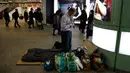 Seorang tunawisma Toshihiro Masuda (59) mengganti pakaian tidur di Stasiun Shinjuku, Tokyo, Jepang, Kamis (9/1/2020). Puluhan tunawisma tidur nyenyak di stasiun kereta bawah tanah Tokyo. (AP Photo/Jae C. Hong)