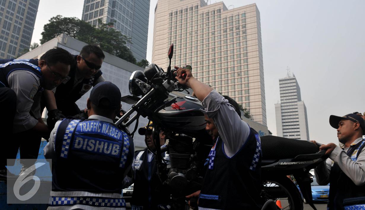 Petugas Dishub, mengangkut sepeda motor saat razia gabungan di kawasan Tanah Abang, Jakarta, Jumat (12/6/2015). Razia gabungan Dishub, Garnisun dan Satlantas bertujuan untuk mengantisipasi arus lalu lintas yang kerap macet. (Liputan6.com/Johan Tallo)