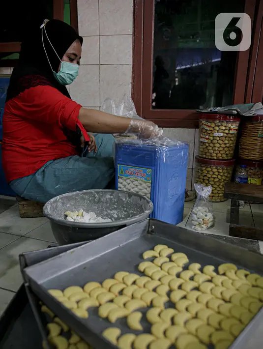 Pekerja memasukan kue kerineg ke dalam kaleng di sebuah industri rumahan di Kawasan Kwitang, Jakarta, Jumat (30/4/2021). Pandemi Covid-19 yang masih terjadi berimbas pada industri rumahan kue kering tersebut. (Liputan6.com/Faizal Fanani)