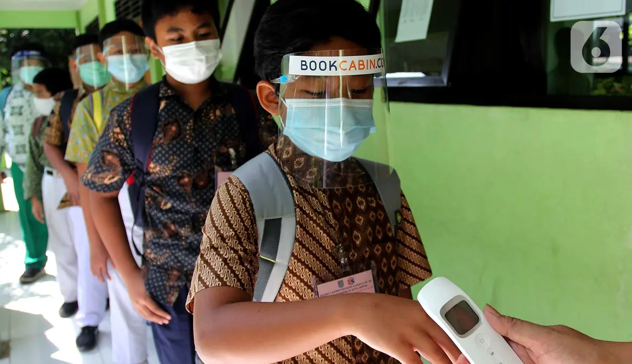 Murid di tes suhu tubuh sebelum mengikuti kegiatan Kompetisi Sains Nasional (KSN) seleksi Tingkat SD/ MI se-Kota Depok mata pelajaran IPA di SDN Kemirimuka 3, Depok, jawa Barat, Senin (22/3/2021). Pelaksanaan KSN diikuti perwakilan murid  dari 11 kecamatan di wilayah Depok. (merdeka.com/Arie Basuki)
