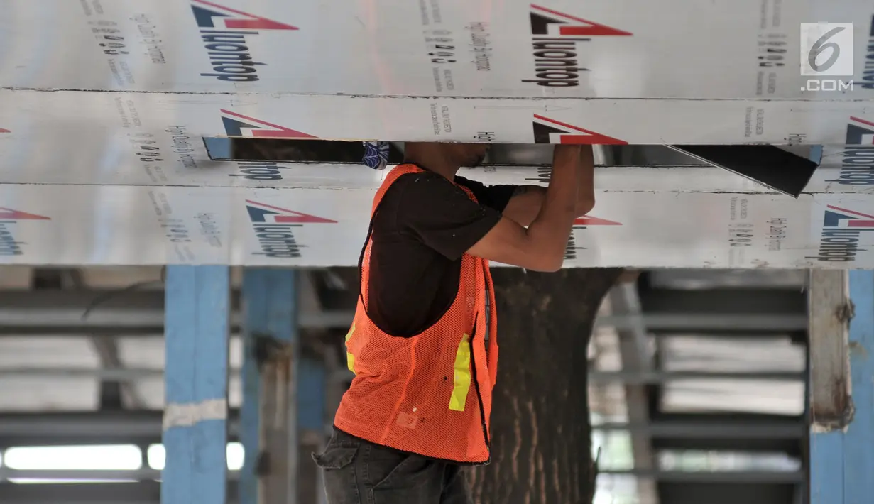 Pekerja merapikan langit-langit Halte Bus Transjakarta Gelora Bung Karno (GBK) di Jalan Jenderal Sudirman, Jakarta, Selasa (24/7). (Liputan6.com/Faizal Fanani)