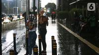Warga melintasi jalan saat hujan di kawasan Bundaran Hotel Indonesia, Jakarta, Senin (1/11/2021). BMKG mengeluarkan peringatan dini cuaca ekstrem berupa hujan dengan intensitas sedang hingga lebat untuk berbagai wilayah di Indonesia hingga 6 November 2021. (Liputan6.com/Faizal Fanani)