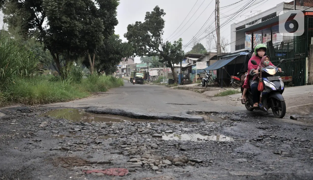 Pengendara motor melintasi jalan rusak dan berlubang di Jalan Tegar Beriman, Cibinong, Bogor, Minggu (31/5/2020). Sudah berbulan-bulan akses yang dikenal sebagai jalan Pemda Cibinong ini sangat memprihatinkan hingga sering menyebabkan kecelakaan terlebih saat musim hujan. (merdeka.com/Iqbal Nugroho)