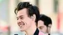 Jas pink yang dipadupadankan dengan kemeja berwarna hitam bikin senyum dan wajah Harry Styles makin bersinar, ya! (Kevin Mazur/Getty Images)