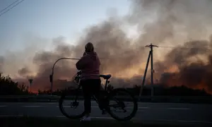 Seorang warga setempat melihat gudang yang terbakar setelah serangan drone Rusia di wilayah Kyiv, Ukraina, pada 20 September 2026, di tengah invasi Rusia ke Ukraina.(Genya SAVILOV / AFP)