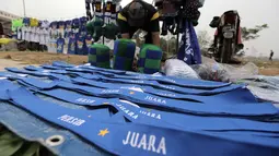 Seorang pedagang atribut merapikan dagangannya di Stadion Si Jalak Harupat, Bandung, Sabtu (24/10/2015). (Bola.com / Nicklas Hanoatubun)