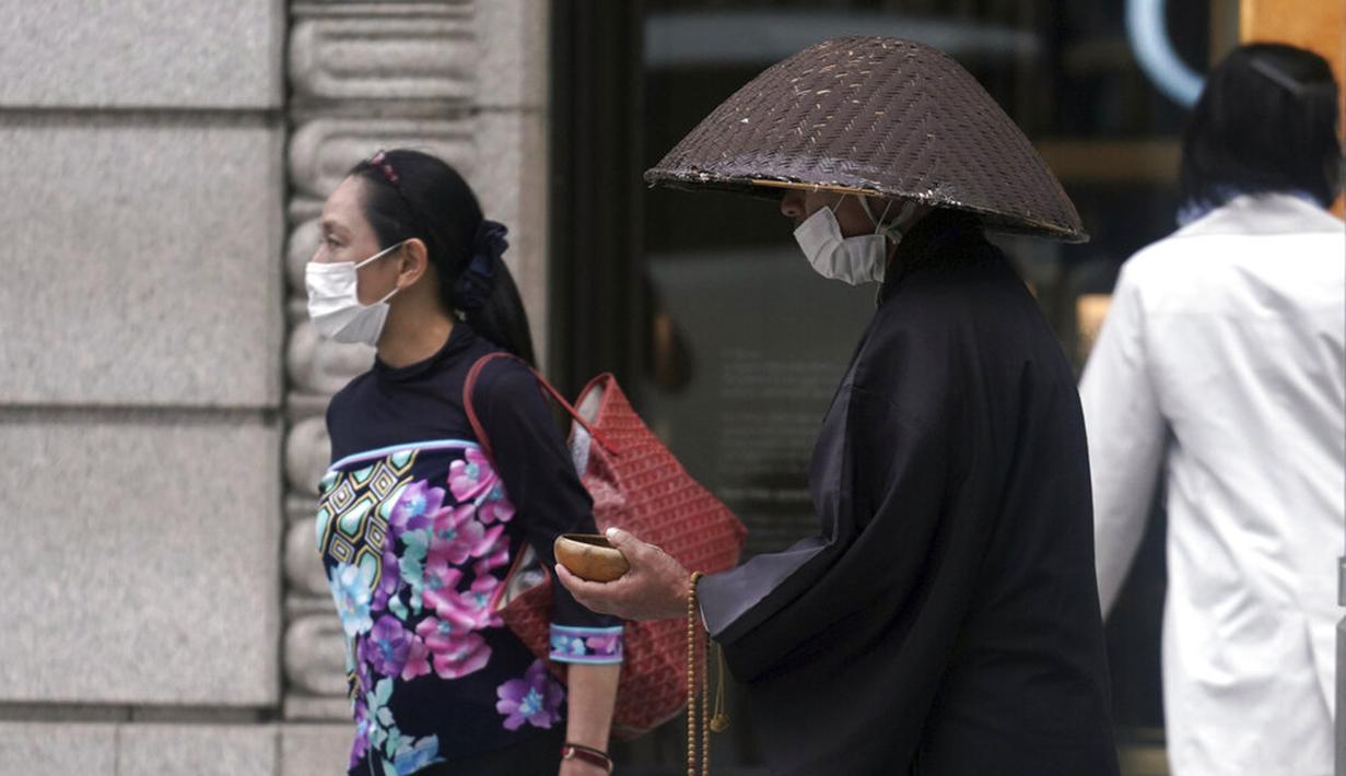 Seorang biksu Buddha yang mengenakan masker untuk membantu mengekang penyebaran virus corona COVID-19 berdoa di distrik perbelanjaan Ginza, Tokyo, Jepang, Rabu (28/10/2020). Tokyo mengonfirmasi lebih dari 170 kasus virus corona COVID-19 baru pada 28 Oktober 2020. (AP Photo/Eugene Hoshiko)