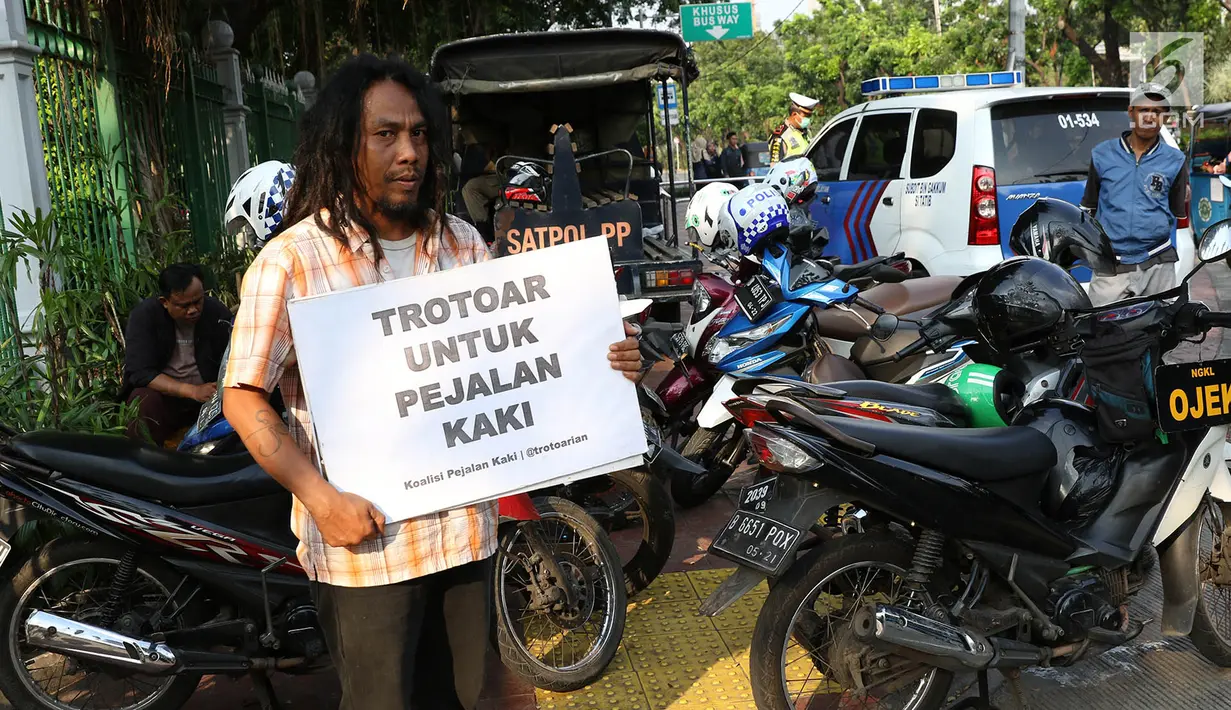 Aktivis melakukan aksi di sepanjang trotoar kawasan Monas, Jakarta, Jumat (28/7). Aksi tersebut dilakukan untuk mengembalikan fungsi trotoar sebagai tempat bagi pejalan kaki yang sering diokupasi oleh kendaraan bermotor. (Liputan6.com/Immanuel Antonius)