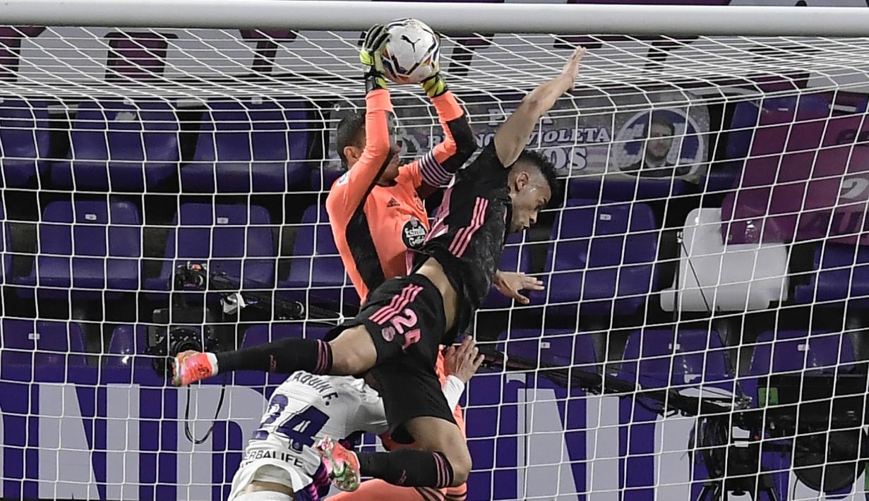 Kiper Real Valladolid, Jordi Masip, berebut bola dengan pemain Real Madrid, Mariano Diaz, pada laga Liga Spanyol di Stadion Jose Zorrila, Minggu (21/2/2021). Real Madrid menang dengan skor 1-0. (AP/Alvaro Barrientos)