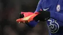 Salah satu official dari Chelsea pun segera mencari pengganti sepatu untuk Cucurella. Alih-alih mengganti sepansang, pemain 24 tahun itu ternyata hanya mengganti sepatu kirinya yang rusak. (AP/Kin Cheung)