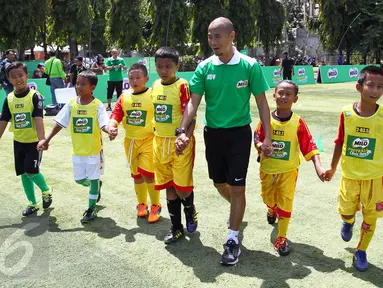 Kurniawan Dwi Yulianto bersama peserta MILO Football Clinic Day memasuki lapangan sepak bola di Lapangan Sepakbola Pertamina-Simprug, Jakarta (29/10). Sebanyak 600 siswa Sekolah Dasar di Jakarta ikut dalam pelatihan sepak bola. (Liputan6.com/Istimewa)