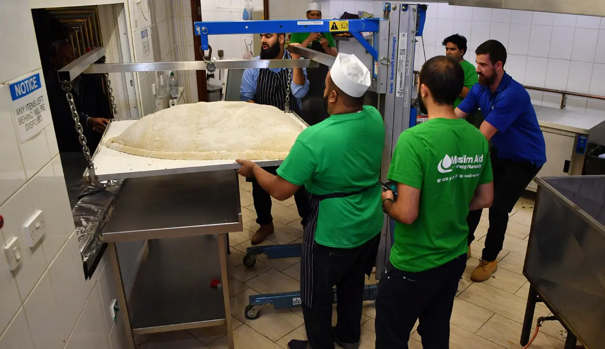 Koki dan relawan Muslim Aid menimbang berat makanan ringan berbentuk segitiga, samosa raksasa, di Masjid London Timur, London, Inggris, Selasa (22/8). Dibutuhkan 6 orang dan wajan khusus untuk menggoreng samosa raksasa ini. (BEN STANSALL/AFP)