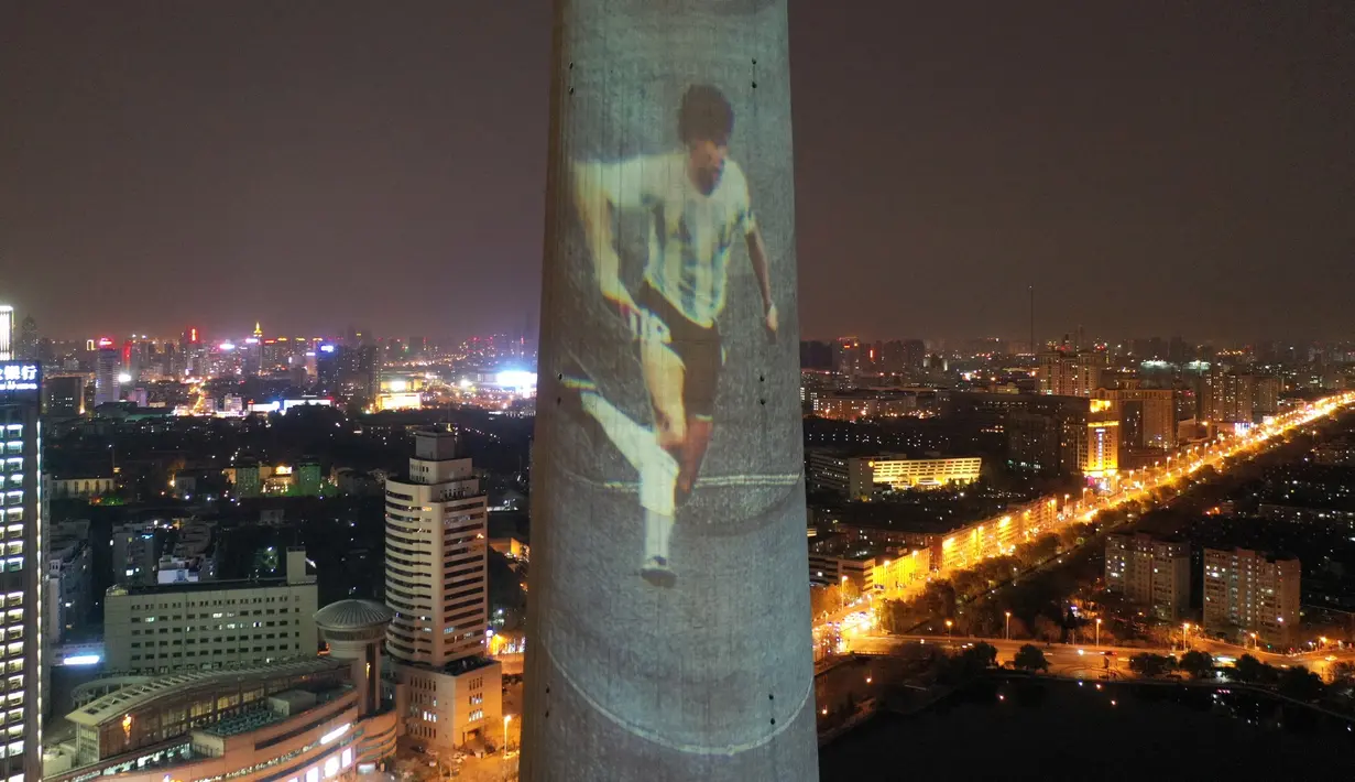 Foto dari udara menunjukkan gambar legenda sepak bola Diego Maradona yang diproyeksikan di Menara TV Tianjin di Kota Tianjin, China utara (26/11/2020). Maradona tutup usia di usia 60 tahun akibat serangan jantung pada Rabu (25/11). (Xinhua/Li Ran)