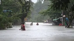 Warga menerobos banjir yang merendam di kecamatan Mawlamyine, negara bagian Mon, Myanmar (18/6). Beberapa wilayah di negara bagian Mon, menghadapi banjir akibat hujan deras sejak akhir pekan lalu. (AFP PHOTO / Ye Aung Thu)