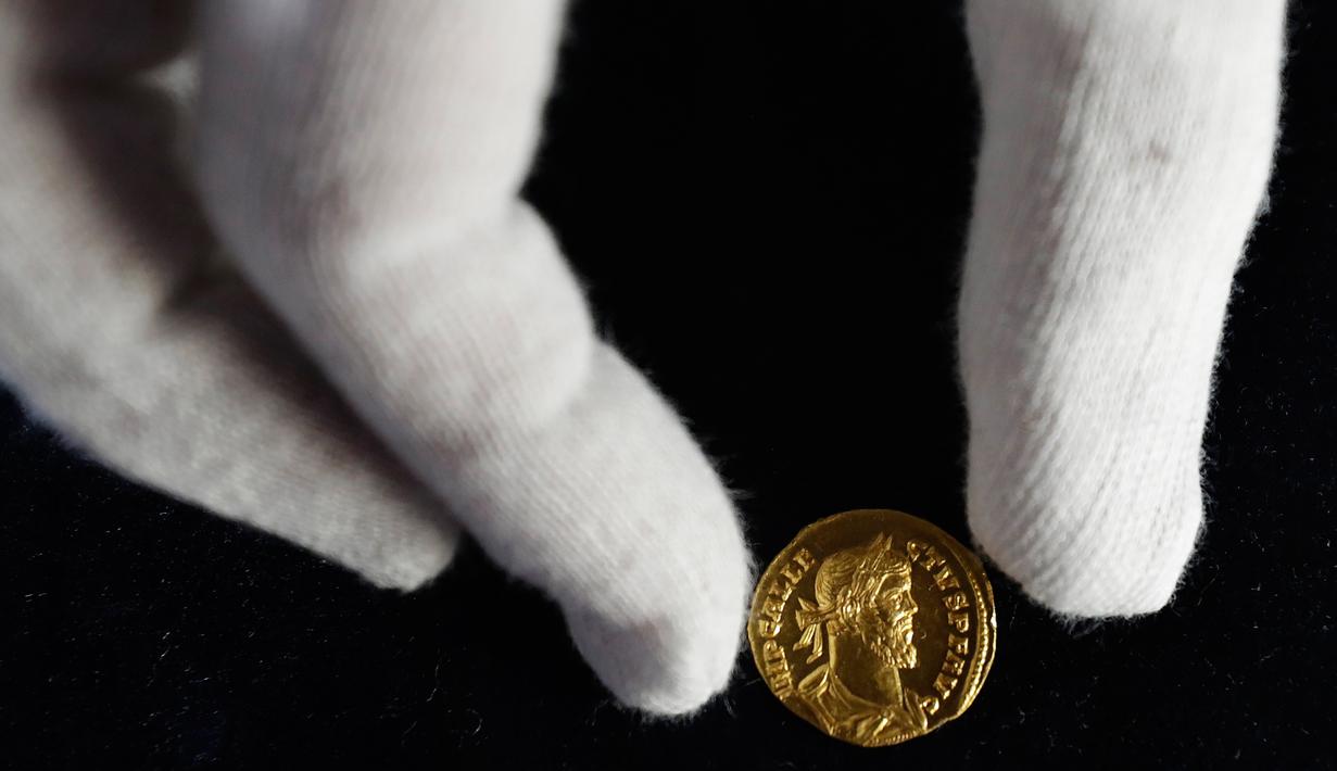 Seorang karyawan Dix Noonan Webb menunjukkan koin Romawi kuno di London, Inggris (28/5/2019). Koin emas ini diperkirakan akan mendapatkan jumlah enam angka ketika itu ditawarkan oleh Dix Noonan Webb dalam lelang dua hari mereka pada bulan Juni. (AP Photo/Kirsty Wigglesworth)