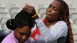 Petenis putri AS, Venus Williams, merapikan rambut adiknya, Serena Williams, saat latihan jelang Olimpiade Rio 2016 di Olympic Tennis Center, Rio de Janeiro, Brasil, (3/8/2016). (AFP/Luis Acosta)