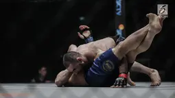 Petarung Rusia, Yusup Saadulaev (atas) berusaha mengunci petarung Jepang, Masakazu Imanari saat berlaga pada One Championship di Jakarta Convention Center (JCC), Sabtu (20/1). Pertarungan dimenangkan oleh Yusup Saadulaev. (Liputan6.com/Faizal Fanani)