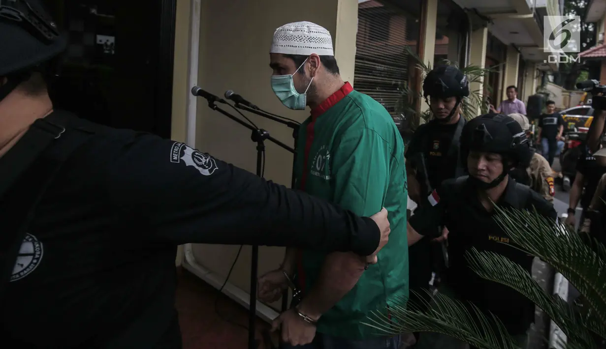 Artis Claudio Martinez memakai masker dengan tangan di borgol usai rilis narkoba di Polres Jakarta Barat, Jumat (9/11). Claudio ditangkap dengan barang bukti 7,96 gram ganja. (Liputan6.com/Faizal Fanani)