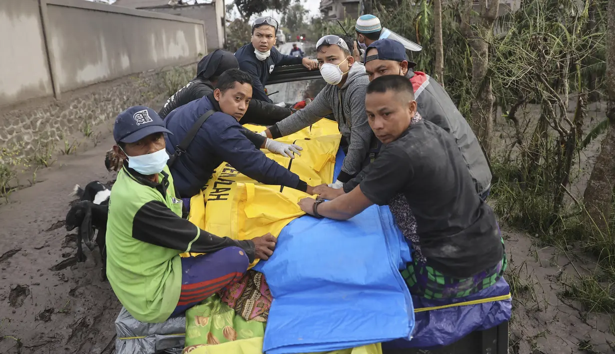 Tim penyelamat dan penduduk desa mengevakuasi korban menggunakan mobil pascaerupsi Gunung Semeru di Lumajang, Jawa Timur, 5 Desember 2021. Dari 14 korban meninggal dunia, belum semua jasad teridentifikasi. (AP Photo/Trisnadi)