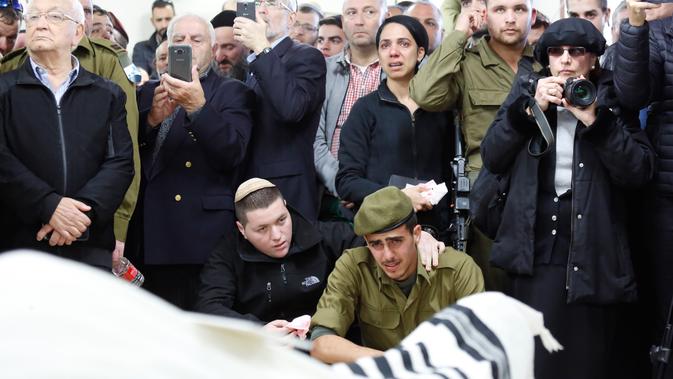 Tentara Israel dan kerabat Yosef Cohen menangis saat pemakamannya di Yerusalem, Jumat (14/12). Penembakan terhadap dua tentara Israel terjadi beberapa jam setelah pasukan Israel menembak mati dua warga Palestina di Tepi Barat. (AP Photo/Ariel Schalit)