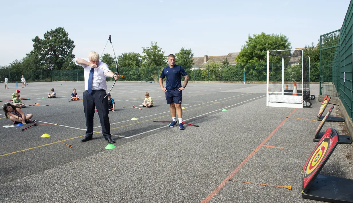 PM Inggris Boris Johnson bermain panahan saat mengunjungi Premier Education Summer Camp di Sacred Heart of Mary Girl's School, Upminster, Inggris, Senin (10/8/2020). Kunjungan Boris untuk melihat persiapan jelang pembukaan kembali sekolah pada September mendatang. (Lucy Young/Pool via AP)