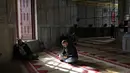 Secara harfiah, Kubah Shakhrah berarti “kubah batu”, ini adalah bangunan persegi delapan berkubah emas yang berdiri di tengah kompleks Masjid Al Aqsha di Yerusalem Timur. Tampak dalam foto, seorang pria Palestina membaca Al-Quran di dalam Kubah Batu, kompleks Masjid al-Aqsa, Yerusalem menjelang waktu berbuka puasa selama bulan suci Ramadan 1447 Hijriah pada Rabu 25 Februari 2026. (AHMAD GHARABLI/AFP)