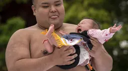 Sumo yang terkenal dengan olahraga gulat tradisional dari Negeri Sakura tersebut berubah menjadi ajang adu tangis para bayi. (AFP/Yuichi Yamazaki)