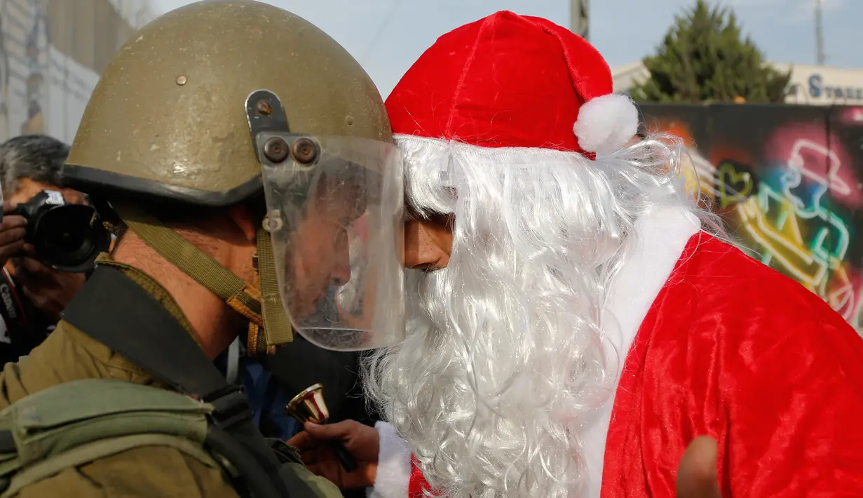 Pengunjuk rasa berkostum sinterklas (Santa Claus) berargumen dengan polisi perbatasan Israel dalam demonstrasi di Bethlehem, Tepi Barat, 23 Desember 2017. Protes terkait pengakuan Donald Trump atas Yerusalem sebagai Ibu Kota Israel. (AP/Nasser Shiyoukhi)