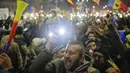 Pengunjuk rasa berkumpul di pusat Bucharest sambil melambai-lambaikan bendera, Rumania, Minggu (5/2). Mereka bersorak mendengar pengumuman yang dikeluarkan setelah unjuk rasa selama hampir 1 minggu. (AP Photo)