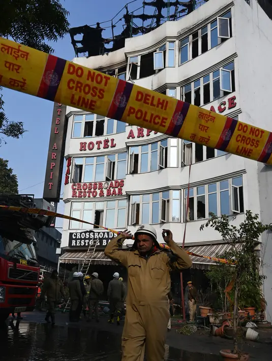 Personel kepolisian berada di luar Hotel Arpit Palace yang terbakar di Distrik Karol Bagh, New Delhi, Selasa (12/2). Sebanyak 20 truk pemadam kebakaran dikerahkan ke lokasi setelah panggilan darurat pada subuh waktu setempat. (Prakash SINGH / AFP)