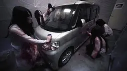 Para pemeran zombie membersihkan darah palsu pada kendaraan saat demonstrasi pertunjukan rumah hantu drive-in di Tokyo, Jepang, Selasa (18/8/2020). Rumah hantu drive-in ini diadakan di tengah pandemi COVID-19. (AP Photo/Eugene Hoshiko)