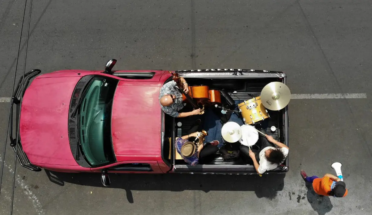 Band Maroto Jazz Trio yang terdiri dari Diego Maroto pada Saxophone, Jorge Molina pada double bass, dan Edy Vega pada drum tampil dari atas sebuah van melewati kawasan Mexico City, Meksiko, 29 Agustus 2020. Penampilan mereka dilakukan di tengah pandemi virus corona COVID-19. (RODRIGO ARANGUA/AFP)