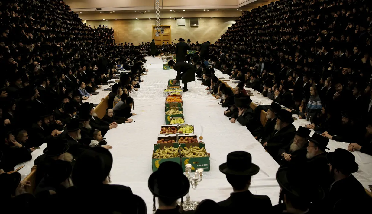 Sejumlah pria Yahudi Ultra-Orthodoks dari dinasti Belz Hasidic duduk sekitar meja makan yang sudah disediakan buah-buahan untuk memperingati perayaan Tu Bishvat, hari Arbor Yahudi di Jerusalem, (25/1).  (REUTERS/Ronen Zvulun)