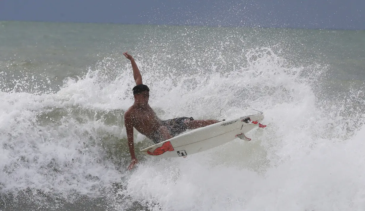 Abu Dzar Al-Ghifari berselancar di lepas pantai Carita, Banten (26/12). Pemerintah meminta warga menghindari pantai di daerah-daerah tersebut di mana tsunami telah menewaskan 420 jiwa akhir pekan lalu. (AP Photo/Achmad Ibrahim)