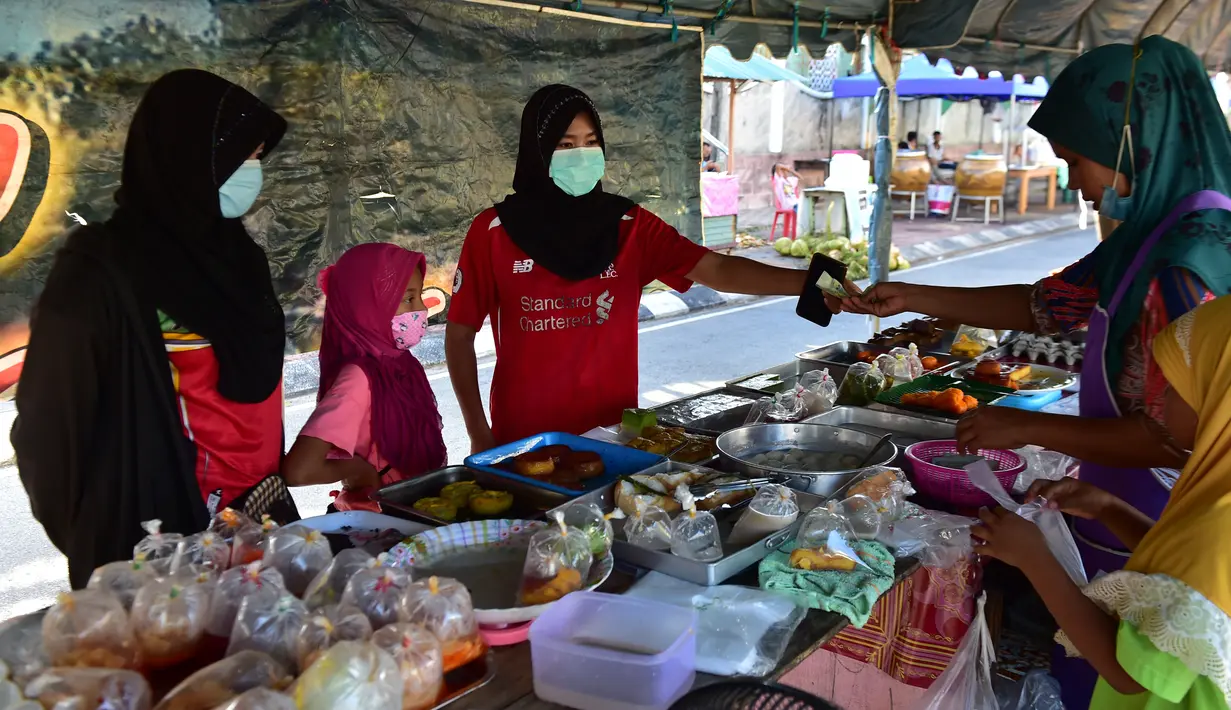 Orang-orang mengenakan masker saat membeli makanan di pasar menjelang berbuka puasa selama bulan suci Ramadan di Provinsi Narathiwat, Thailand, Selasa (5/5/2020). Ramadan kali ini berlangsung di tengah bayang-bayang virus corona COVID-19. (Madaree TOHLALA/AFP)