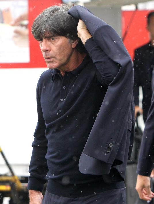 Pelatih Jerman, Joachim Loew, menutup kepalanya karena hujan saat tiba di Moskow, Selasa (12/6/2018). Jerman datang ke Rusia untuk mempertahankan gelar juara Piala Dunia. (AFP/Daniel Roland)