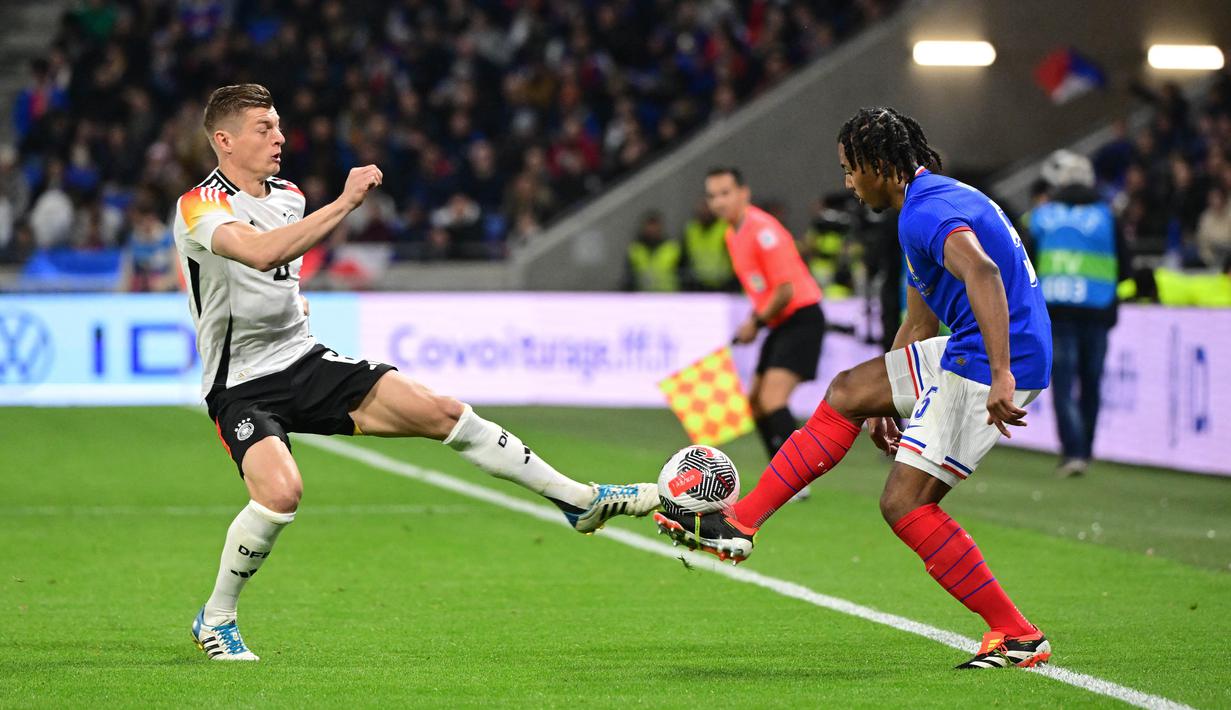 Pemain Jerman, Toni Kroos, berebut bola dengan pemain Prancis, Jules Kounde, pada laga persahabatan di Stadion Groupama, Minggu (24/3/2024). (AFP/Olivier Chassignole)