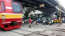 Sejumlah pengendara motor menunggu kereta melintas di perlintasan kereta api di kawasan Roxy, Jakarta, Rabu (21/3). Pembukaan celah untuk akses sepeda motor di pintu perlintasan kereta api tersebut sangat membahayakan. (Liputan6.com/Arya Manggala)