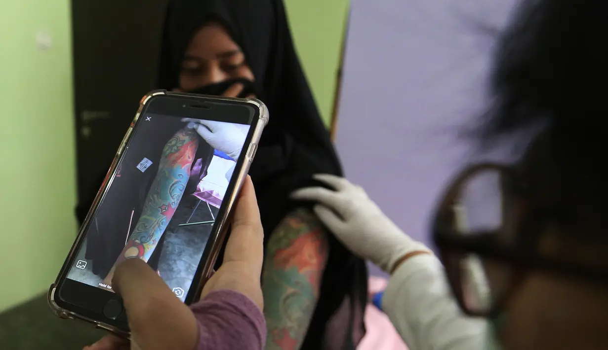 Seorang dokter kulit memeriksa tato di lengan Puji Rahayu sebelum dihapus menggunakan laser di Tangerang (11/8). Hapus tato ini gratis dengan syarat pasien harus membaca dan belajar Alquran Surat Arrahman. (AP Photo/Achmad Ibrahim)