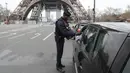 Polisi memeriksa dokumen pengemudi kendraan saat lockdown di depan Menara Eiffel, Paris, Prancis, Rabu (18/3/2020). Otoritas Prancis hanya mengizinan warga keluar rumah untuk alasan penting dan darurat. (Ludovic MARIN/AFP)