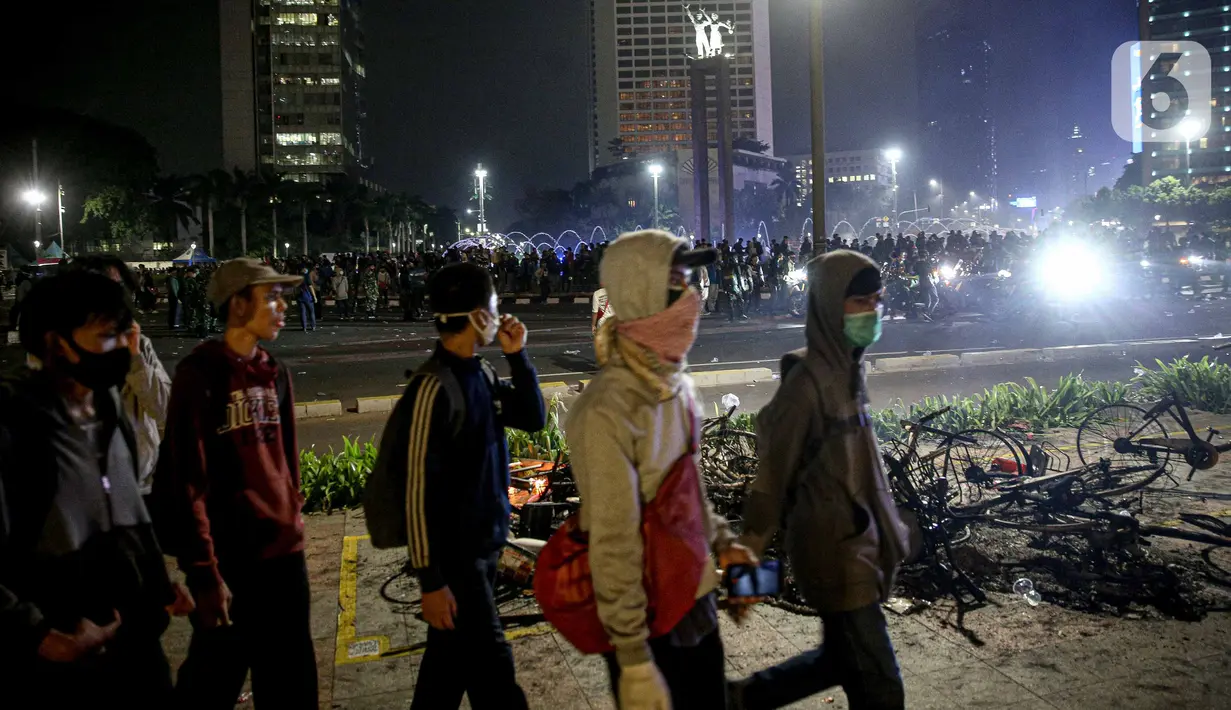Sejumlah orang berjalan usai demonstrasi yang berujung anarkis di kawasan Bundaran HI, Jakarta, Kamis (8/10/2020). Massa membakar sejumlah barang saat demonstrasi menolak pengesahan UU Cipta Kerja. (Liputan6.com/Faizal Fanani)