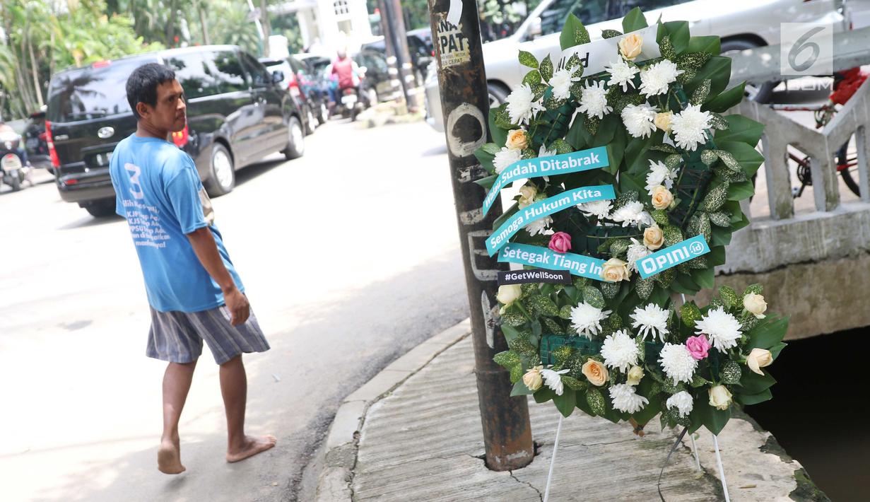 Pejalan kaki mengamati tiang lampu di lokasi kecelakaan Setya Novanto di Jalan Permata Berlian, Jakarta, Sabtu (18/11). Pada karangan itu tertulis pesan "Walau Sudah Ditabrak Semoga Hukum Kita Setegak Tiang Ini #GetWellSoon." (Liputan6.com/Angga Yuniar)