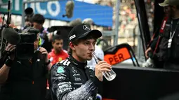 Ia mencatat waktu tercepat 1:28.778 dalam sesi kualifikasi yang digelar di Sirkuit Suzuka, pada Sabtu (28/3/2026). Tampak dalam foto, pembalap Mercedes AMG Petronas asal Italia, Kimi Antonelli, minum air setelah meraih pole position pada sesi kualifikasi Formula 1 GP Jepang 2026 di Sirkuit Suzuka, pada Sabtu (28/3/2026). (Philip FONG/AFP)