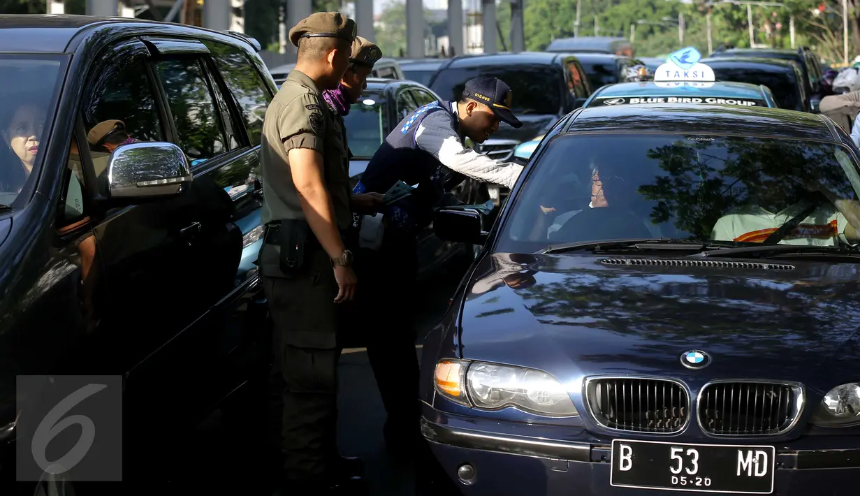 Petugas membagikan brosur uji coba penerapan sistem ganjil genap di Bundaran Senayan, Jakarta, Rabu (27/7). Kebijakan pembatasan kendaraan dengan penerapan pelat ganjil genap dimulai hari ini hingga tanggal 26 Agustus. (Liputan6.com/Gempur M Surya)