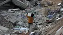 <p>Saat ini jutaan anak masih menghadapi masalah-masalah yang sering membuat mereka merasa terancam hingga menimbulkan rasa takut. Tampak dalam foto, seorang anak laki-laki Palestina membawa sebuah wadah plastik saat dia berjalan melewati puing-puing di samping sebuah bangunan yang hancur akibat pemboman Israel baru-baru ini di Khan Yunis di Jalur Gaza selatan pada 19 November 2024. (Eyad BABA/AFP)</p>