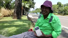 Sambil tersenyum, Ibu Tuti menunjukan ponsel baru miliknya hasil pemberian Gubernur DKI Jakarta, (24/3). Wanita 54 tahun ini mendapatkan hadiah ponsel karena aksinya yang berani memarahi pendemo perusak Balai Kota. (Liputan6.com/Yoppy Renato)