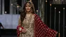 Seorang model mengenakan busana rancangan desainer Faike Karim selama Bridal Couture Week di Lahore, Minggu (9/12). Kreasi gaun pengantin yang ditampilkan didominasi kain sari yang menjadi ciri khas wanita Pakistan. (AP Photo/K.M. Chaudary)