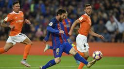 Bintang Barcelona, Lionel Messi, berusaha melewati pemain Osasuna pada laga La Liga di Stadion Camp Nou, Barcelona, Rabu (26/4/2017). Barcelona menang 7-1 atas Osasuna. (AFP/Lluis Gene)