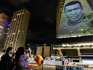 Seorang wanita mengambil gambar mendiang pemain sepak bola Pele yang ditampilkan pada Gedung Federasi Industri Sao Paulo di Sao Paulo, Brasil, 29 Desember 2022. Pele yang menghabiskan sebagian besar kariernya bersama Santos FC telah meninggal di Sao Paulo. (AP Photo/Marcelo Chello)